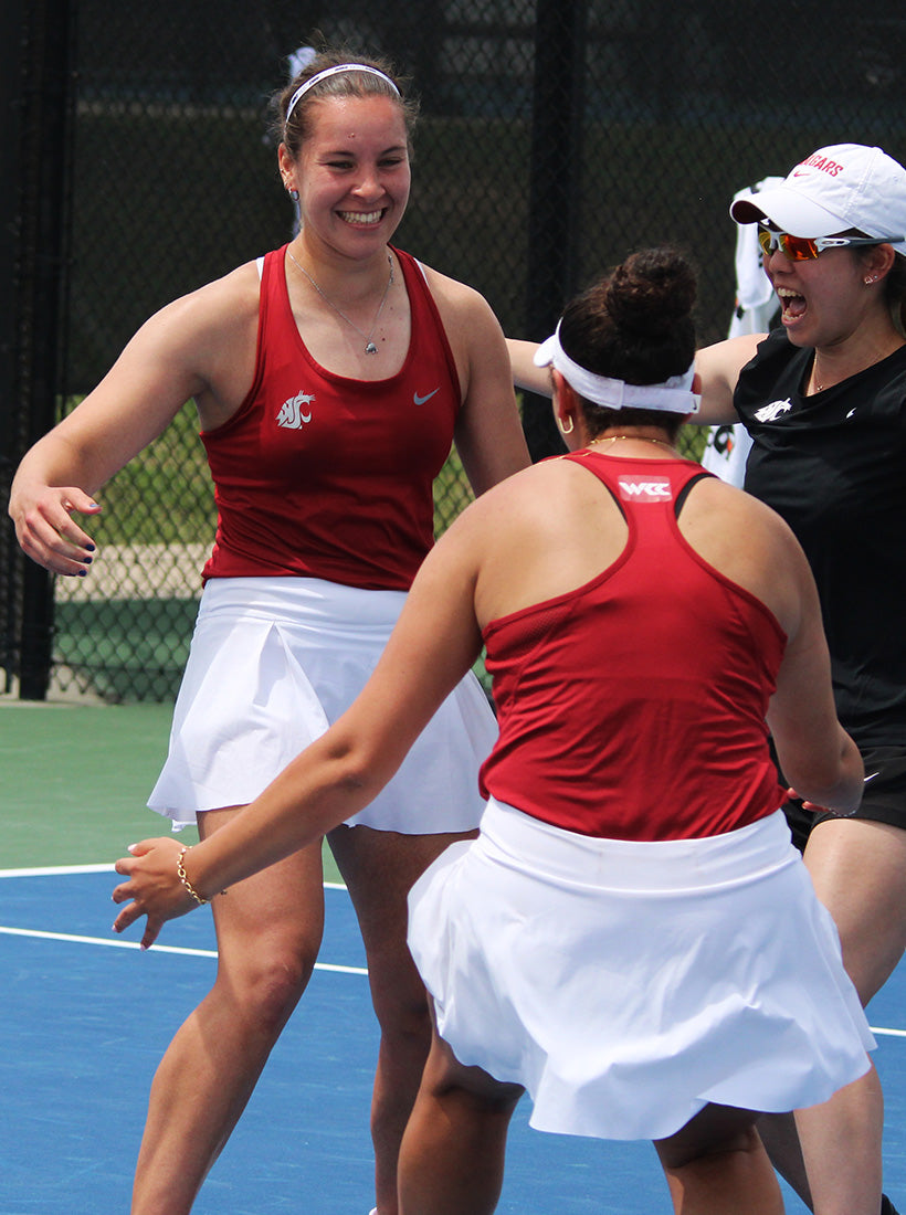 Three women for Washington State University playing tennis on a court with a fence in the background while winning the UTR Sports NIT Championship that supports college tennis