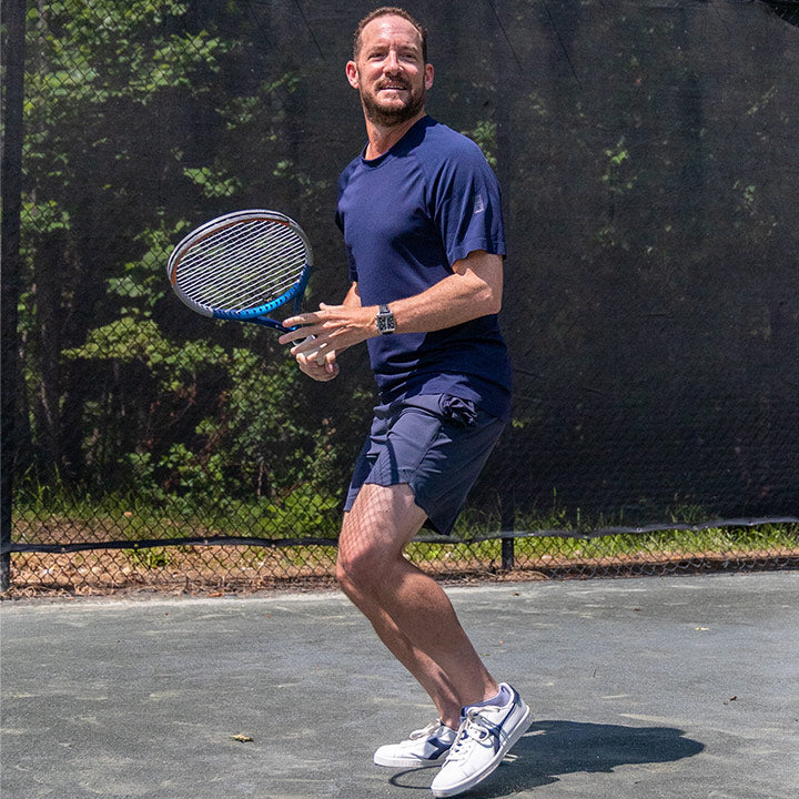 Male tennis player prepares to hit a forehand while wearing Fabletics and improving his UTR Rating, which he can view on Engage API
