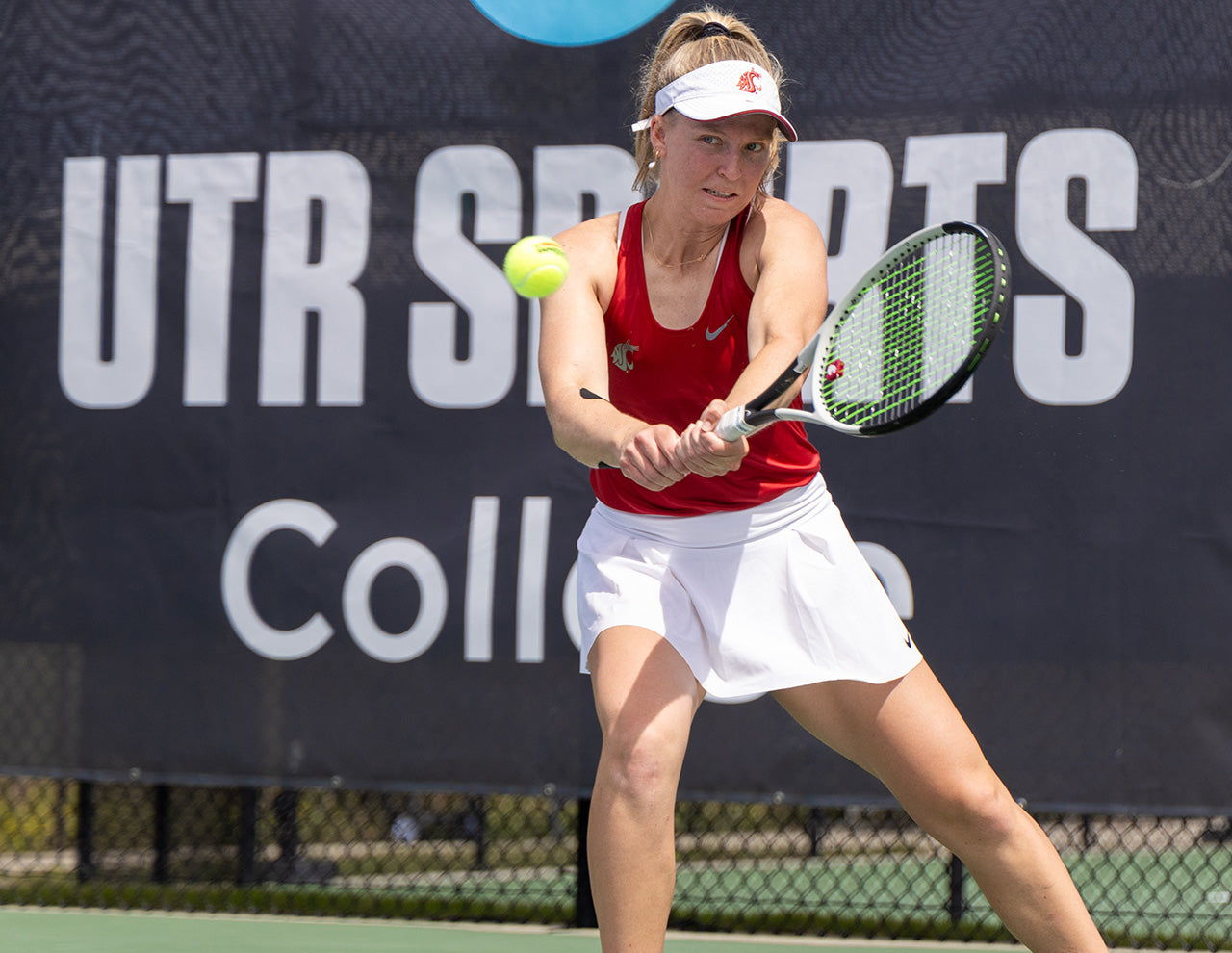 Washington State University women's tennis player hits a backhand while competing at a UTR Sports college tennis tournament